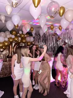 a group of women standing next to each other in front of balloons and streamers