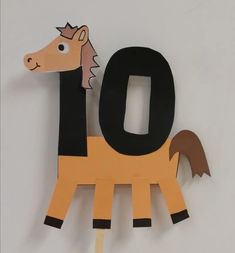 a horse made out of construction paper sitting on top of a white table next to a wall