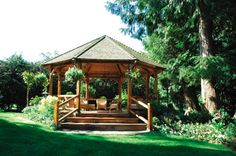 a wooden gazebo sitting on top of a lush green field