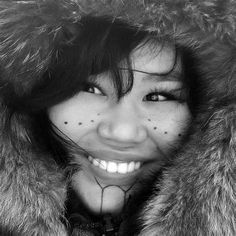 black and white photograph of a woman wearing a fur coat smiling at the camera with her mouth open