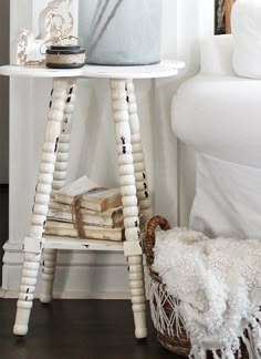 a white table topped with a cake on top of a wooden stand next to a bed