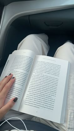 a woman is reading a book in the car