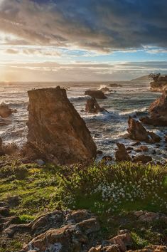 the sun shines brightly on some rocks by the ocean