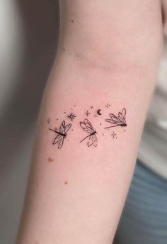 a woman's arm with three small dragon tattoos on the back of her arm