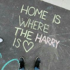 someone standing on the sidewalk with chalk writing in front of them that says home is where the harry is