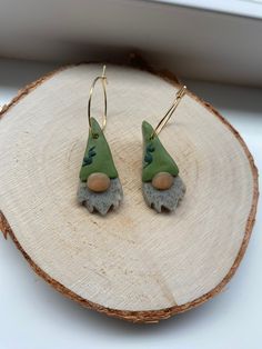 small green and grey gnome earrings sitting on a piece of wood