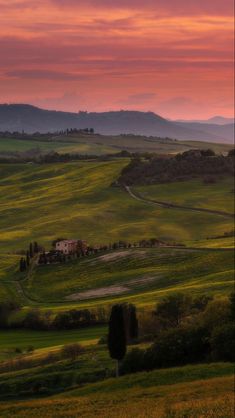 the sun is setting over rolling hills and fields