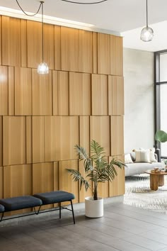 a living room with wood paneling and plants in the corner, along with two black chairs