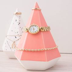 a small pink and white clock sitting on top of a table next to a chain bracelet