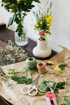 some flowers are sitting on a table with scissors and yarn in front of the vases