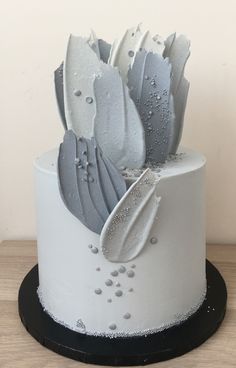 a white and black cake with frosting flowers on the top is sitting on a wooden table