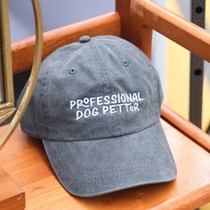 If it's a skill you've got, it's worth showing off! This hat is for all of the professional dog petters out there. Plus, wearing it lets dogs know exactly who to walk up to for the best belly rubs. This hat is a perfect gift for any dog lover in your life. Or maybe even just a gift for yourself! This hat is a faded vintage-style baseball cap that's pigment-dyed slate grey to give it a worn-in look. To adjust the size of this hat, there's a convenient brass clasp closure and an interior pocket to hide the extra material from making it tighter. Every Tay Dunworth hat features a custom, exclusive design and is embroidered in-house in St. Petersburg, FL. Additional Details * Sizing: One size fits most adults * Material: 100% cotton twill * Hat Structure: Unstructured * Hat Profile: Low * Hat C Adjustable Knot, Grey Dog, Stretch Headband, Christmas Headband, Embroidered Hats, Slate Grey, Knot Headband, Dad Hat, Hunter Green