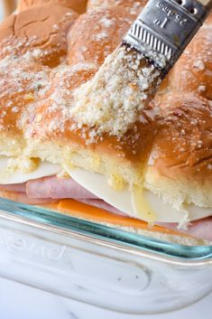 a ham and cheese sandwich in a glass baking dish with a spatula on top