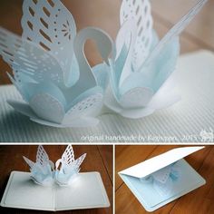 an origami swan with wings on top of a card holder and folded paper