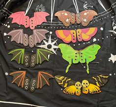 an assortment of colorful bats and moths on a black cloth with stars, beads, and chains