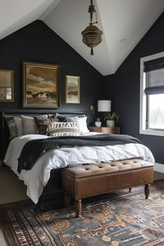 a bedroom with black walls, white bedding and an upholstered footstool