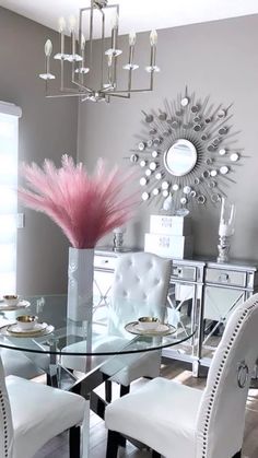 a dining room table with white chairs and a pink centerpiece