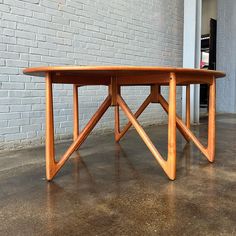 a wooden table sitting on top of a cement floor next to a white brick wall