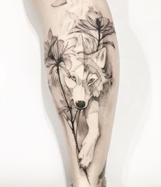 a woman's leg with a wolf and flowers tattoo on it