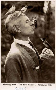 a man with birds on his head looking up at something in the air above him