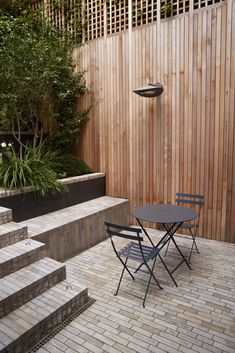 a table and chairs sitting in front of a wooden fence with steps leading up to it