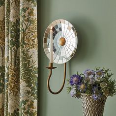 a wall mounted fan next to a vase with flowers