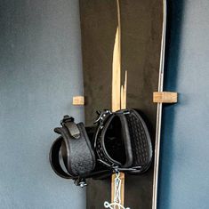 a pair of skis hanging on the wall next to a snowboard and bag