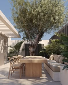 an outdoor living area with couches, tables and a tree