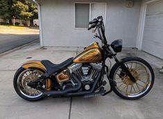 a gold and black motorcycle parked in front of a house