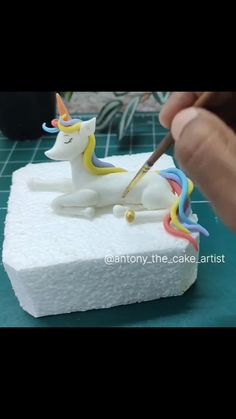 someone is decorating a cake that looks like a unicorn