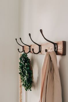 a coat rack with two coats hanging from it's hooks and a wreath on the wall