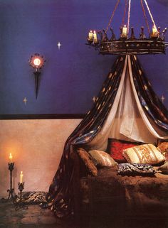 a bedroom with a canopy bed and candles on the wall next to it in front of a chandelier