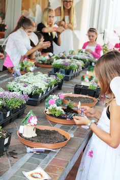 a group of children standing around plants in pots