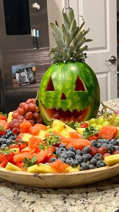 a carved pumpkin sitting on top of a platter of fruit