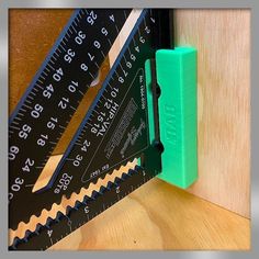 a pair of green rulers and a ruler on a wooden table next to a measuring tape