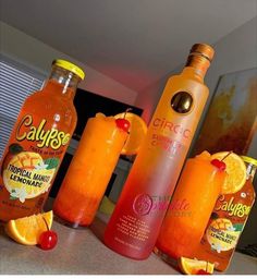 three bottles of orange juice sitting on top of a counter