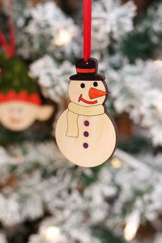 a wooden snowman ornament hanging from a christmas tree