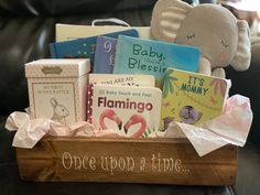 a wooden box filled with books on top of a black leather couch next to a stuffed animal