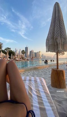 a woman laying on top of a white towel next to a swimming pool with buildings in the background