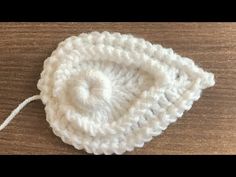 a white crochet hat sitting on top of a wooden table next to a string