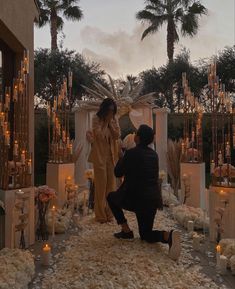 a man kneeling down next to a woman on top of a bed of white flowers