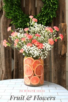 a vase filled with fruit and flowers on top of a table