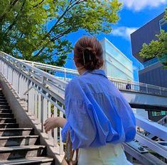 a woman is walking up some stairs with her hand in her pocket and looking at the sky