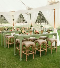 a table and chairs set up in the grass under a tent with white drapes