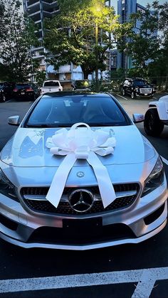 a silver car with a white bow on it's hood parked in a parking lot