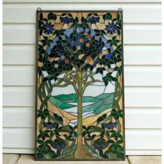 a stained glass panel with a tree and flowers on it's side, in front of a house