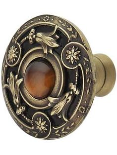 an antique style door knob with a brown stone in the center and flowers on it