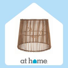 a brown rattan lamp shade sitting on top of a light blue background with the words at home written below it