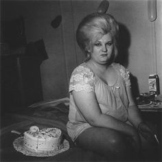 black and white photograph of woman sitting on bed with cake