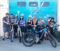 a group of people standing next to bikes in front of a garage